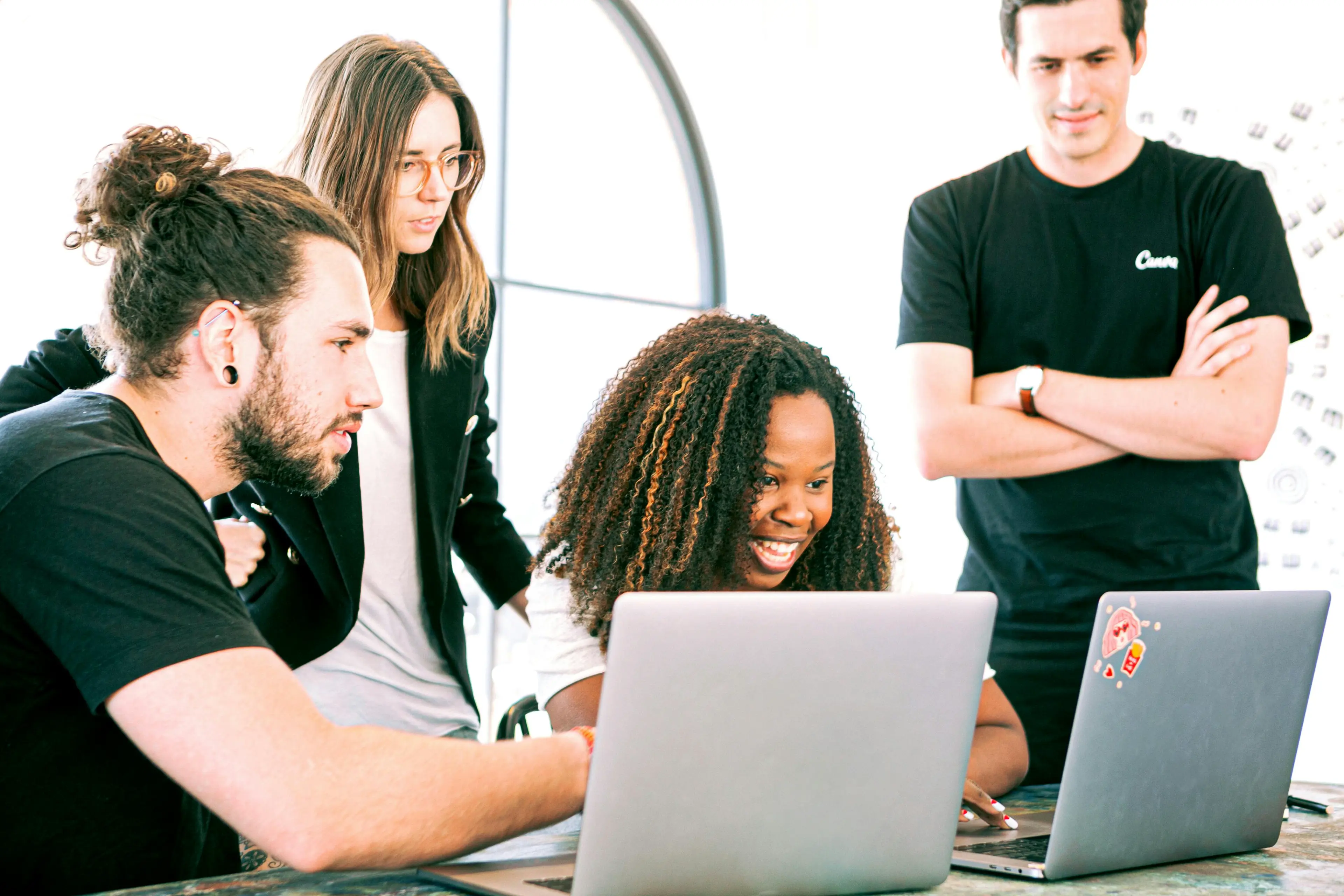 Diverse team collaborating around laptops in bright office