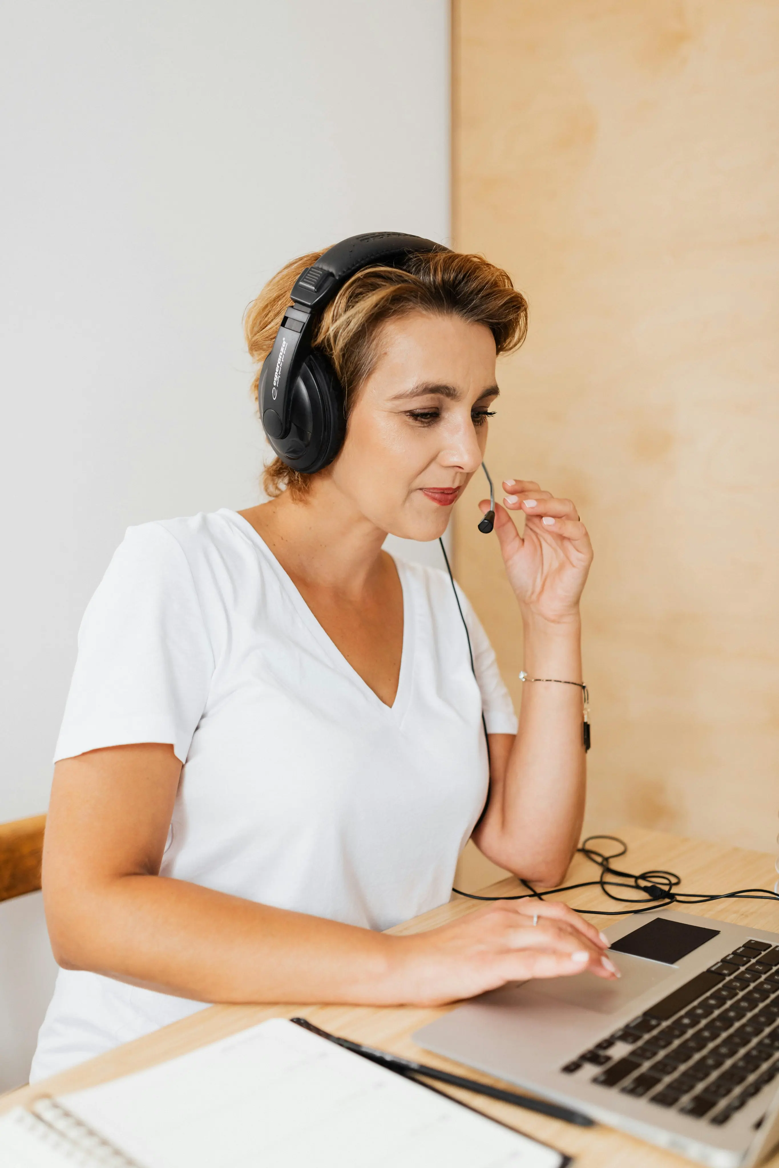 Woman with headset using laptop for virtual meeting